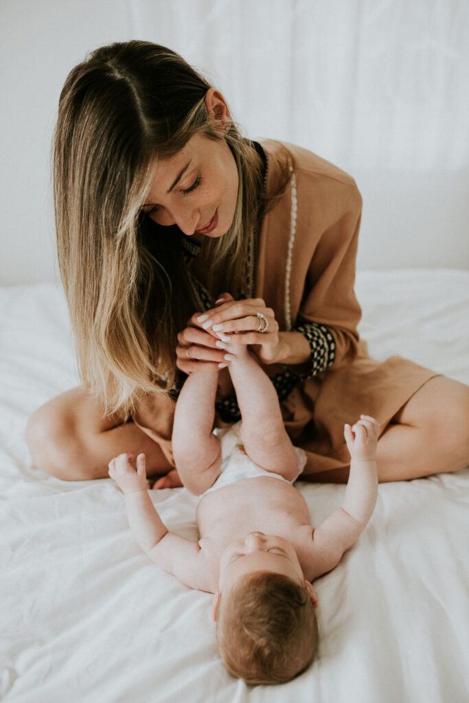 תמונת אוירה: רויטל עם בתה, תינוקת קטנה, שוכבת על גבי מזרון בזמן שרויטל מחזיקה את הרגליים שלה